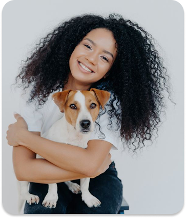 curly woman joyfully embraces cute pet smiling